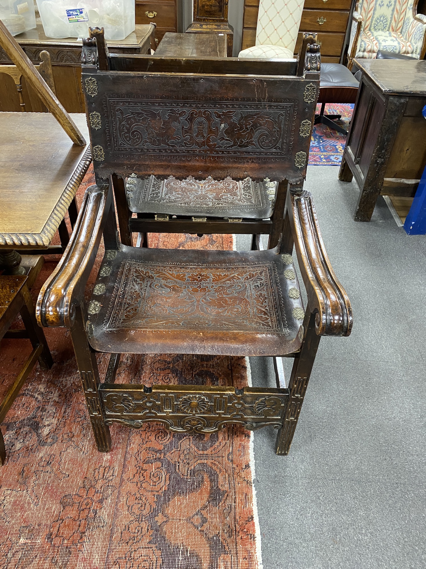 A pair of carved and tooled leather continental elbow chairs, width 68cm, depth 60cm, height 113cm